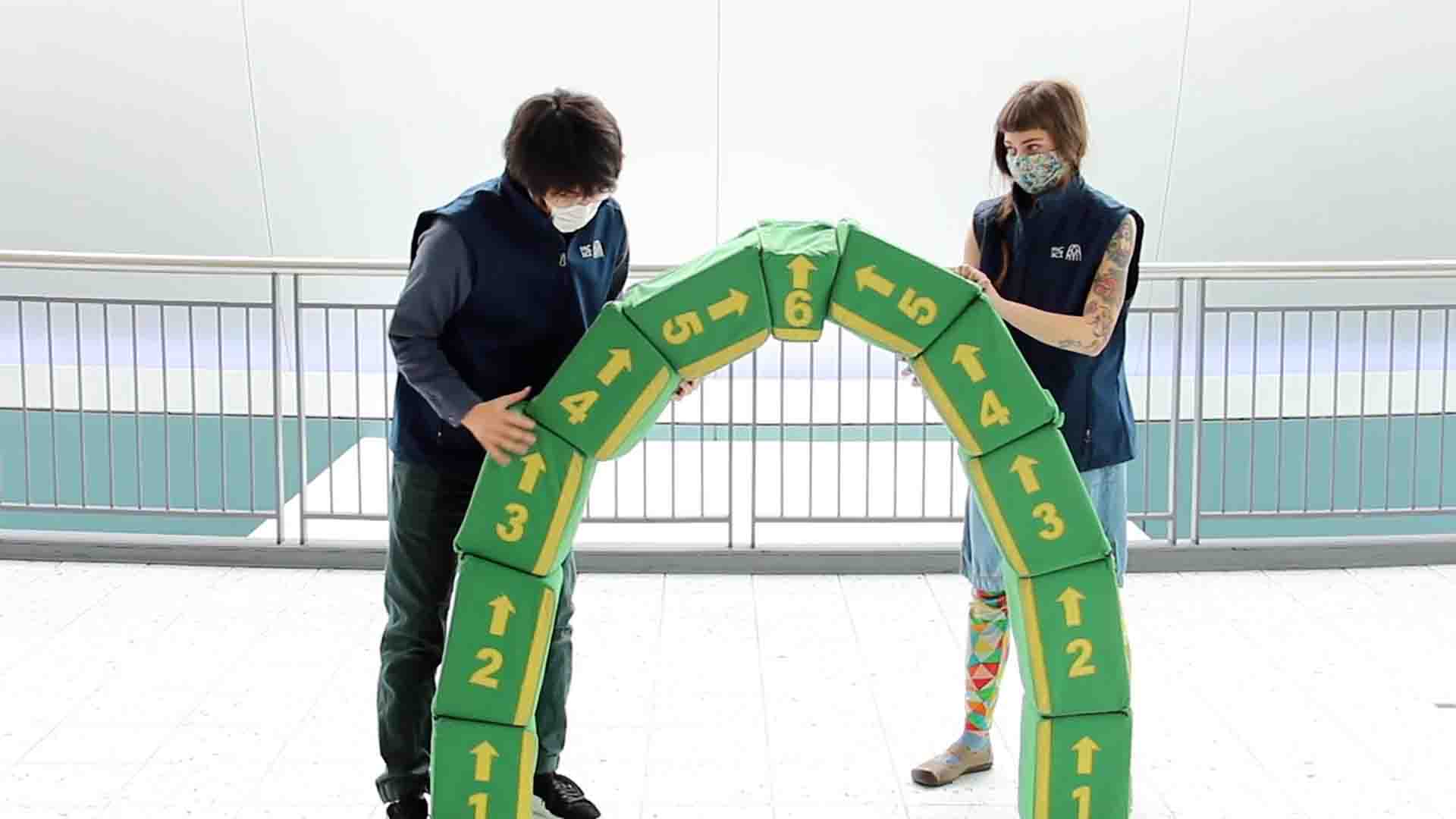 Two people building a green arch