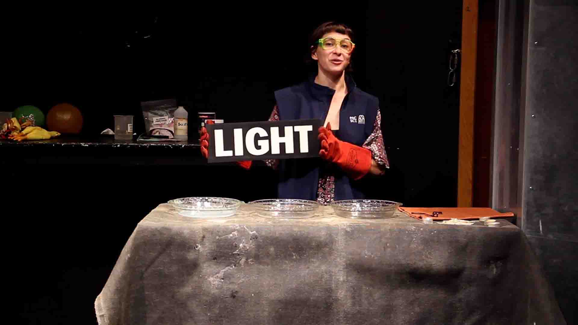 Woman behind a stage holding up a sign saying 