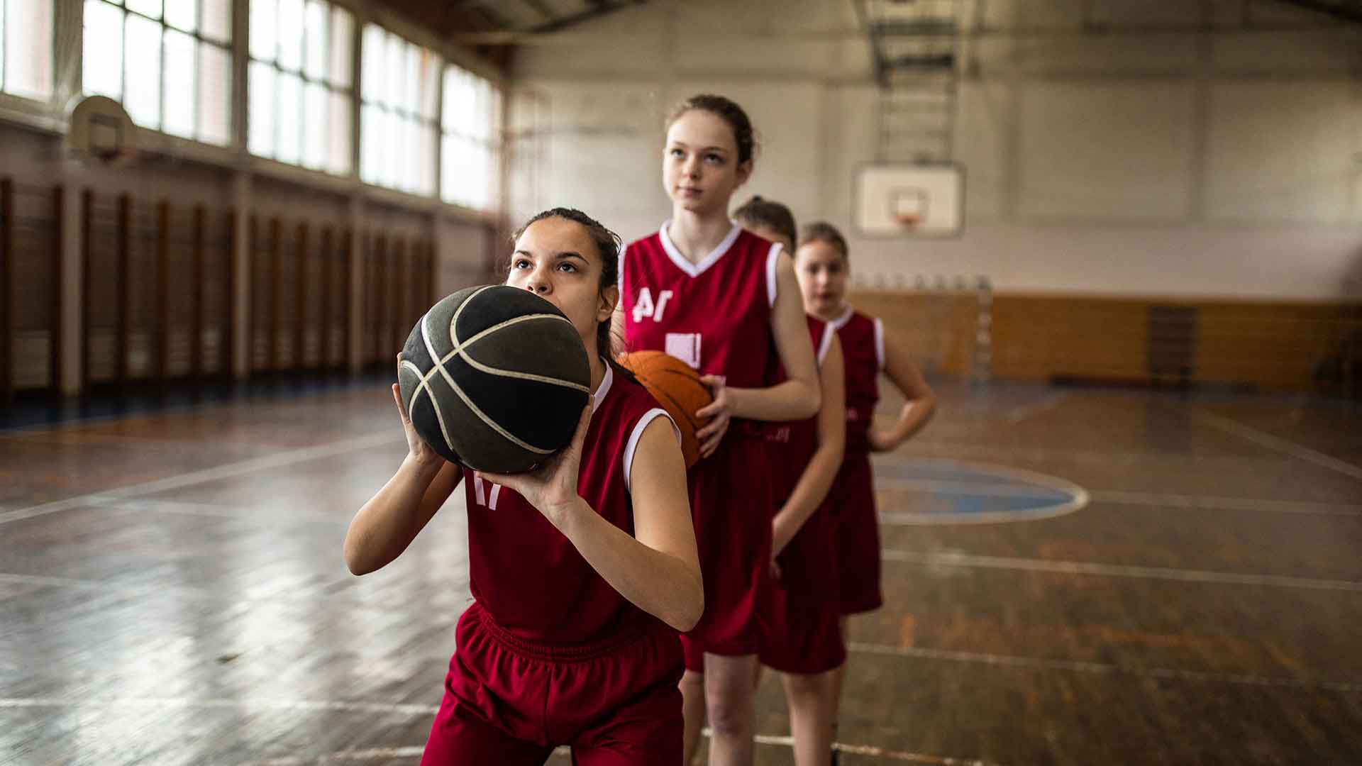 Girls in red jerseys playing basketball