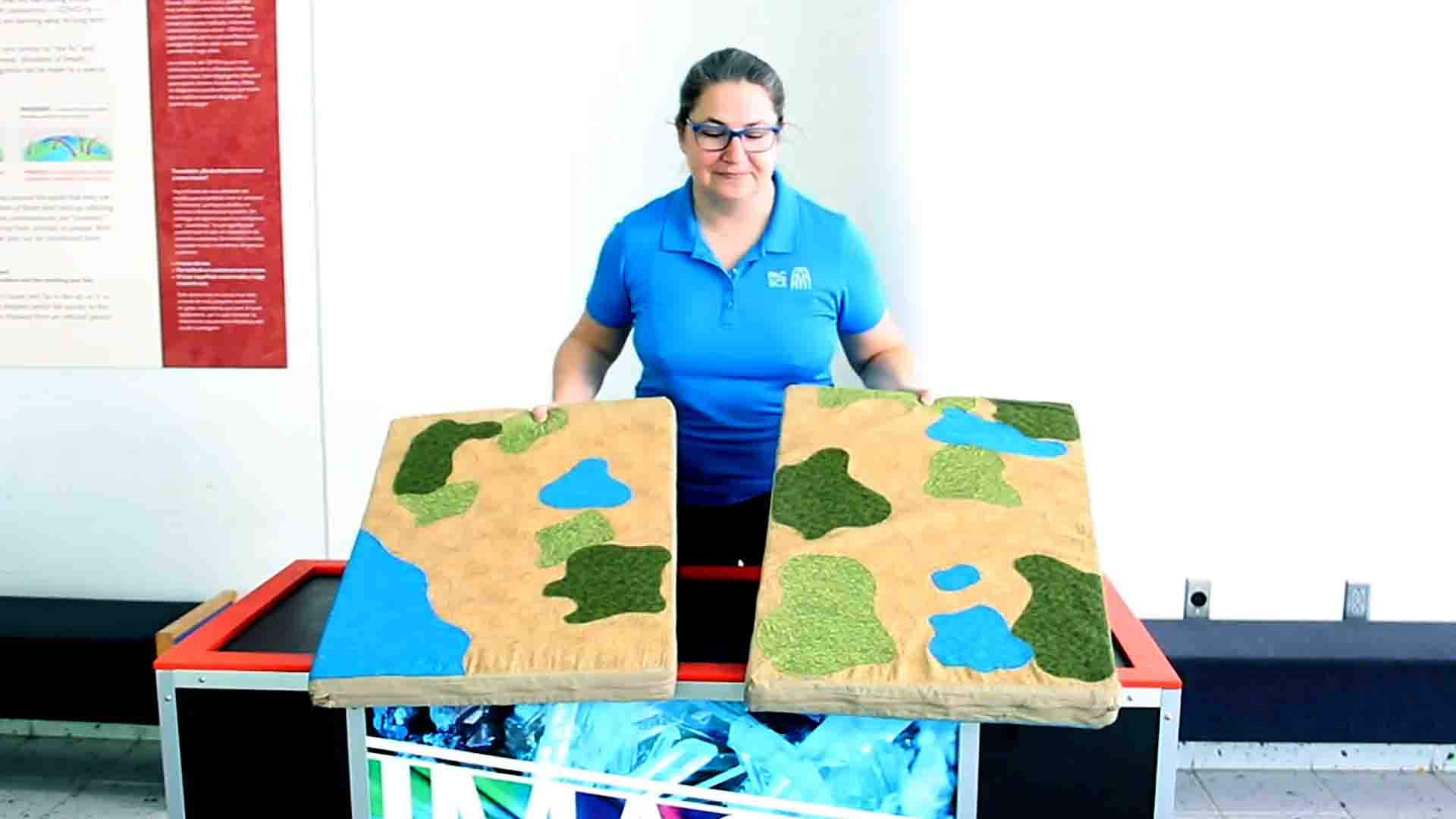 Educator Zeta holds two large pieces representing plate tectonics