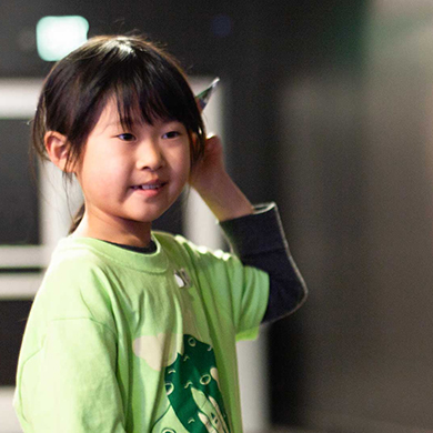 Young girl in green shirt throwing a paper airplane