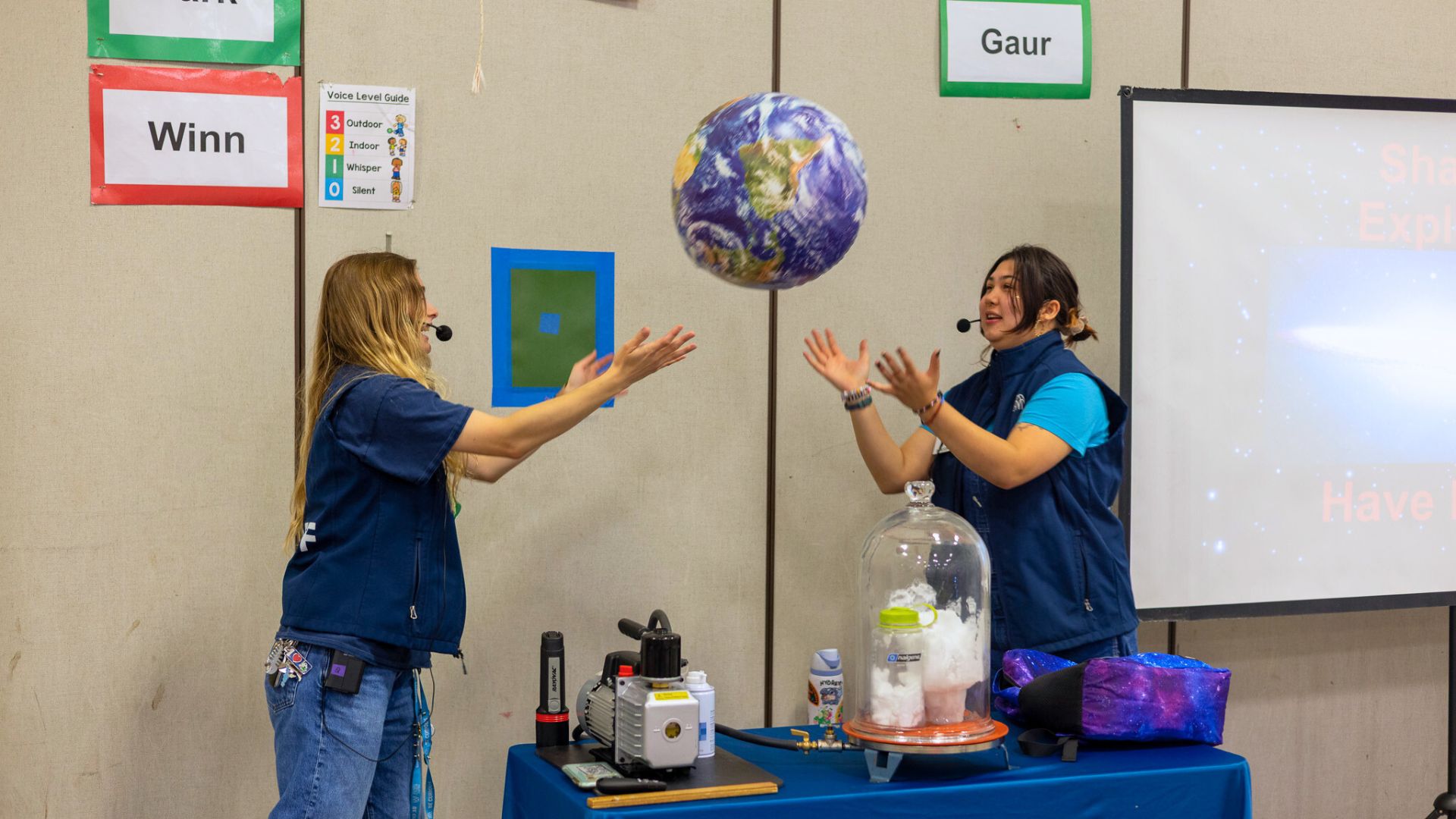 two people throwing a inflatable earth into the air
