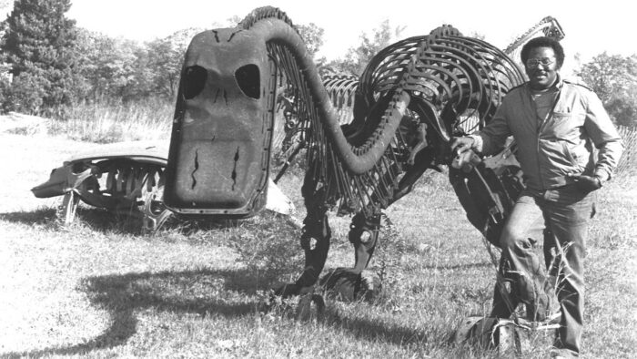 Man standing next to a dinosaur sculpture