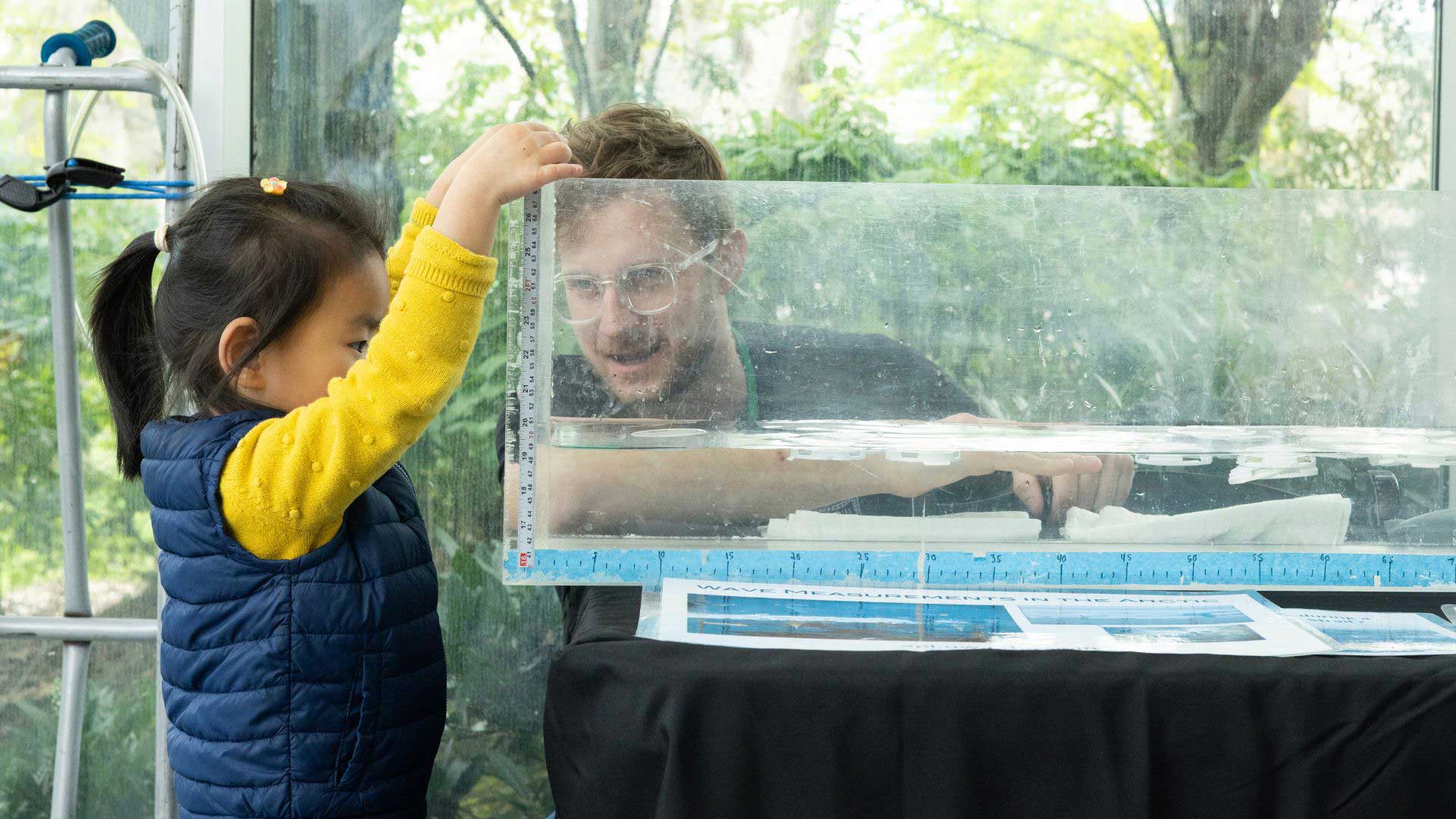 Man with glasses and girl next to a tank of water
