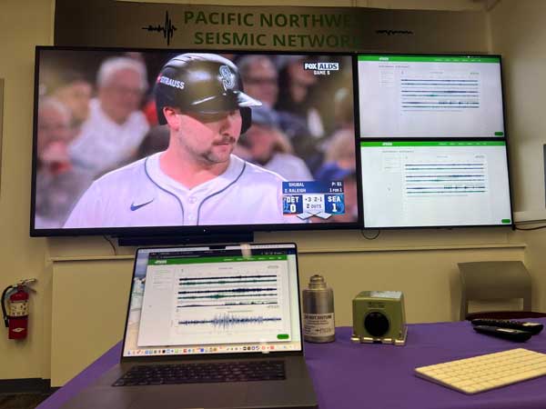 TV with Mariners baseball playoff game and other screens with seismic data