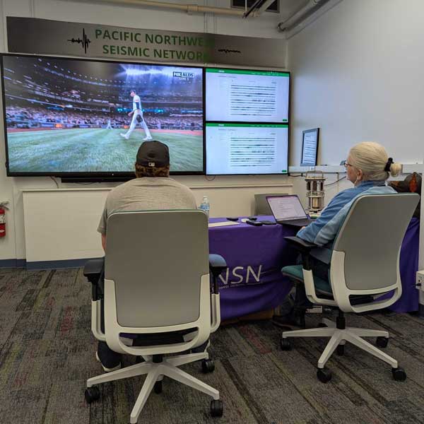 Two PNSN staff members watching the Mariners game with seismic data